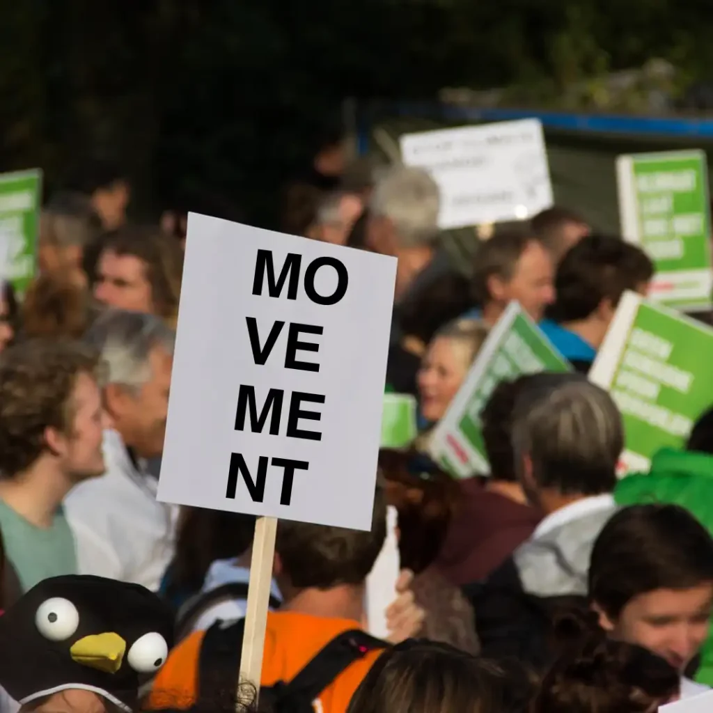 Das Bild zeigt eine Menschenmenge, die demonstriert. Auf einem Schild steht das Wort "Movement" (übersetzt: Bewegung).
